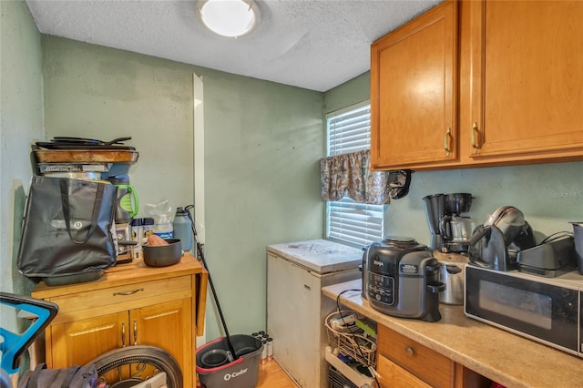 kitchen with a textured ceiling and light wood-type flooring