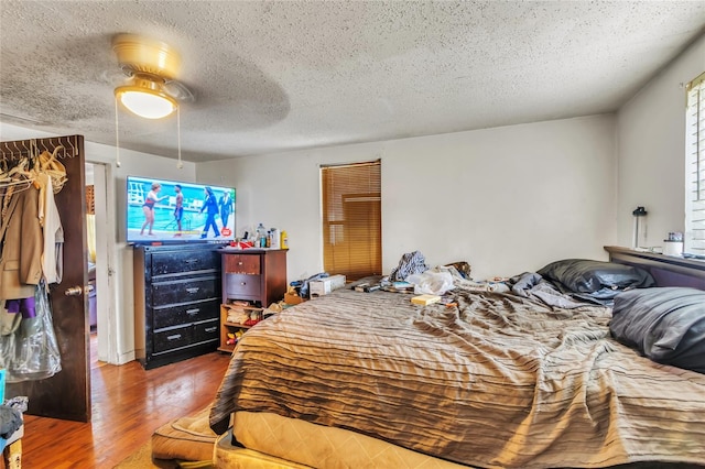 bedroom featuring ceiling fan, wood-type flooring, and a textured ceiling