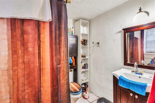 bathroom with vanity, toilet, and a textured ceiling