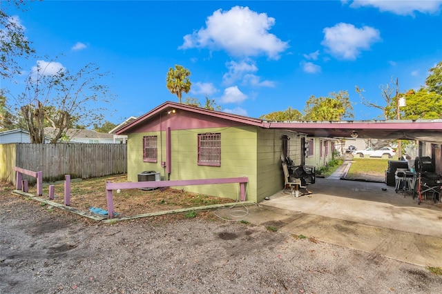 back of house with central AC unit and a carport