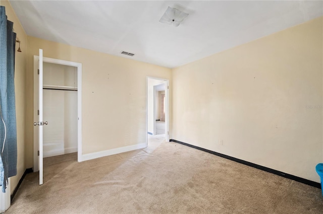 unfurnished bedroom with a closet and light colored carpet