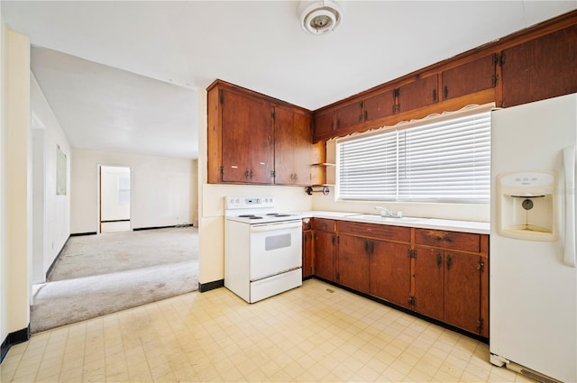 kitchen featuring white appliances, sink, and light carpet