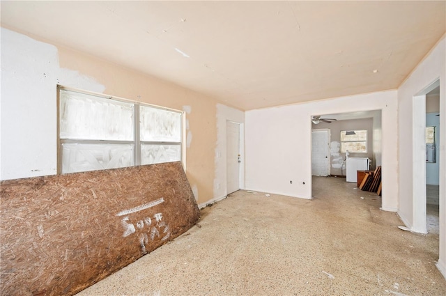 empty room with a wealth of natural light, ceiling fan, and washer / dryer