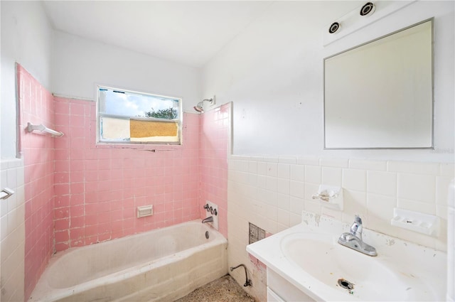 bathroom with vanity, tiled shower / bath combo, and tile walls