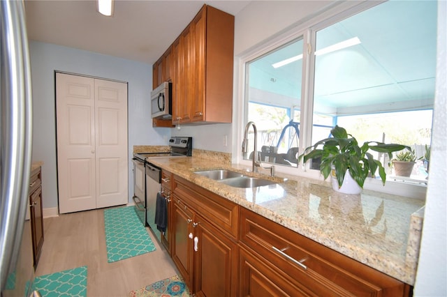 kitchen featuring light stone countertops, light hardwood / wood-style flooring, stainless steel appliances, and sink