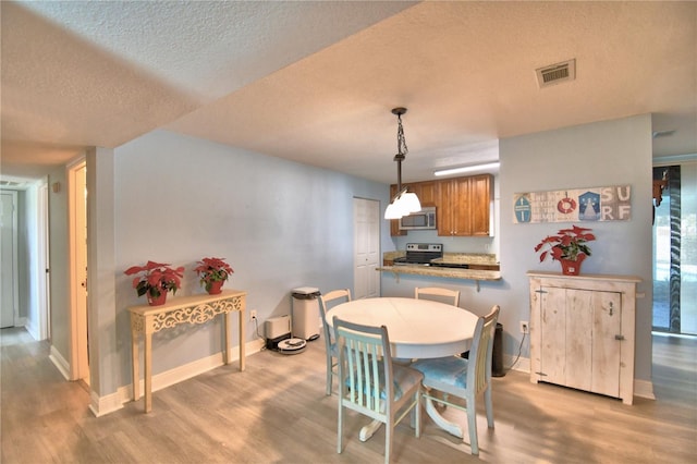 dining space with a textured ceiling and light hardwood / wood-style flooring