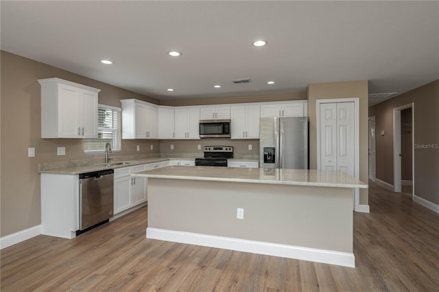 kitchen with white cabinetry, light hardwood / wood-style floors, a center island, and appliances with stainless steel finishes