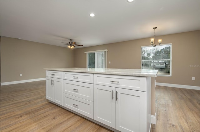 kitchen featuring white cabinetry, decorative light fixtures, light hardwood / wood-style floors, and light stone counters