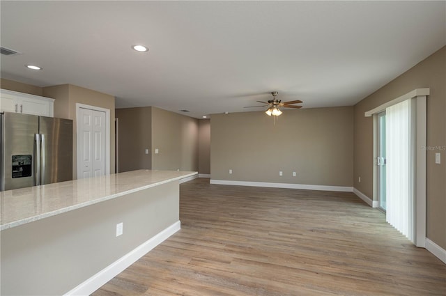 kitchen featuring light hardwood / wood-style flooring, ceiling fan, white cabinetry, light stone counters, and stainless steel fridge with ice dispenser