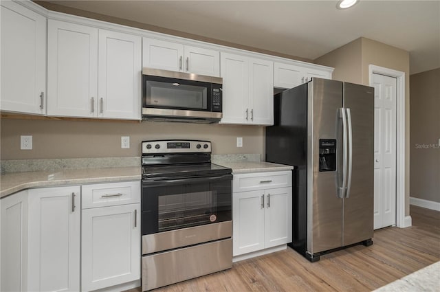 kitchen with light stone countertops, white cabinetry, appliances with stainless steel finishes, and light hardwood / wood-style flooring