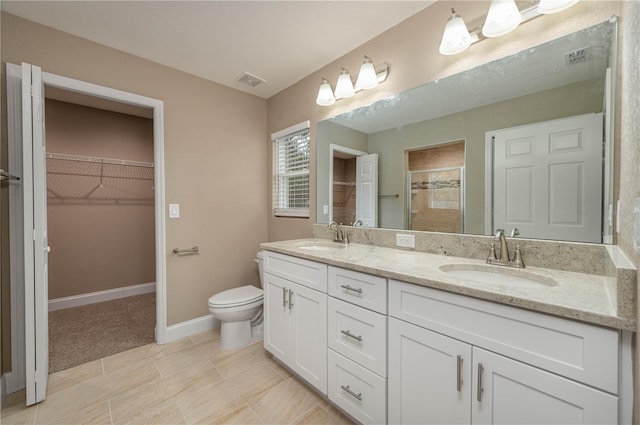 bathroom with toilet, vanity, and a shower with shower door