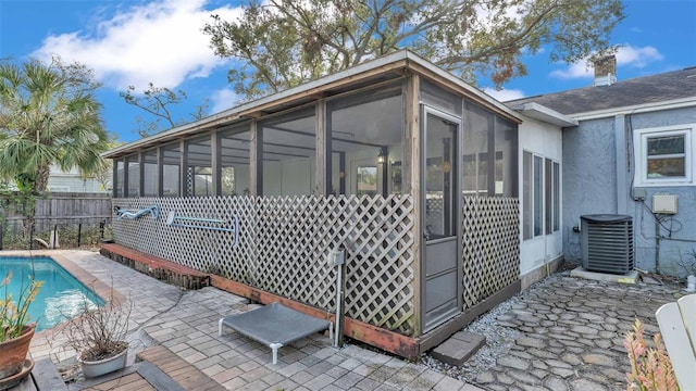 view of property exterior featuring a fenced in pool, a patio, a sunroom, and cooling unit