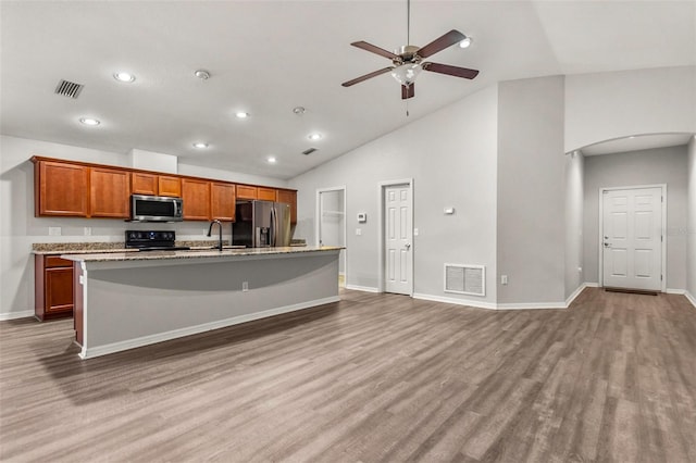 kitchen featuring stainless steel appliances, a kitchen island with sink, ceiling fan, wood-type flooring, and high vaulted ceiling