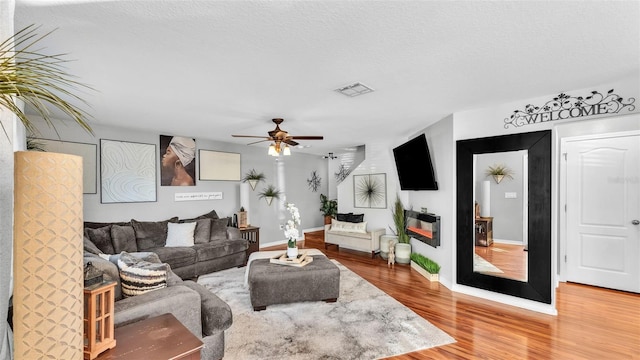 living room featuring ceiling fan, wood-type flooring, and a textured ceiling