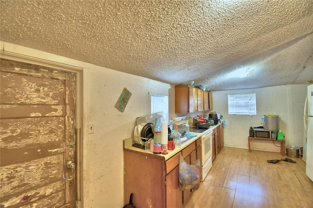 kitchen featuring a textured ceiling, white appliances, and light hardwood / wood-style flooring