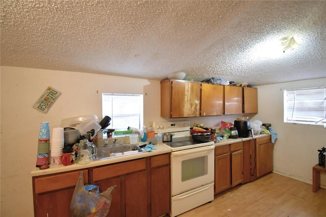 kitchen with a textured ceiling, white stove, light hardwood / wood-style flooring, and sink