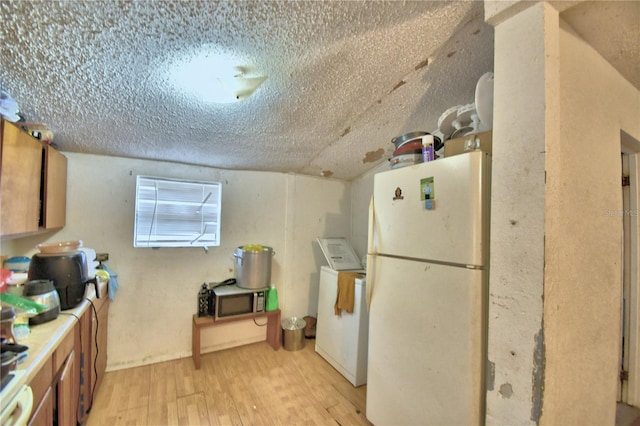 kitchen with light wood-type flooring, a textured ceiling, and white refrigerator