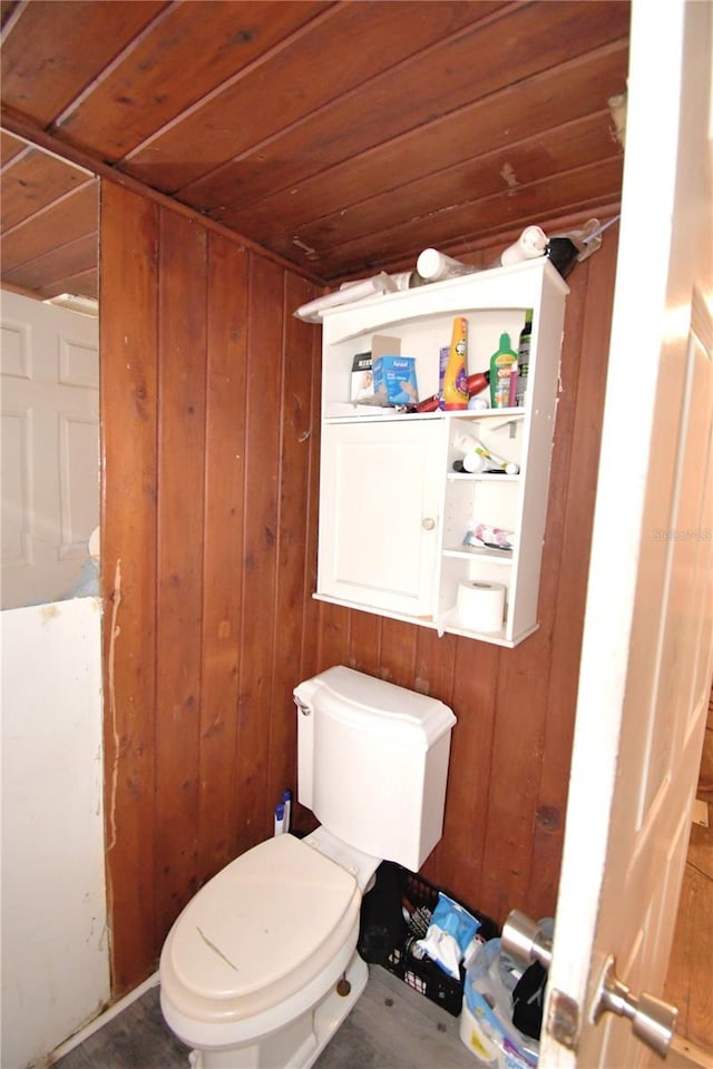 bathroom with toilet, wooden ceiling, and wooden walls