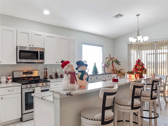 kitchen with a healthy amount of sunlight, white cabinetry, stainless steel appliances, and a kitchen island with sink