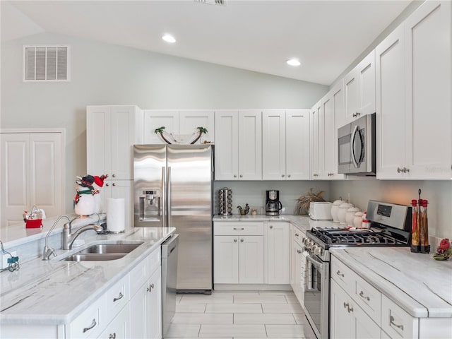 kitchen with light stone counters, sink, stainless steel appliances, and lofted ceiling