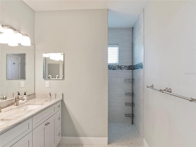 bathroom featuring a tile shower, tile patterned flooring, and vanity