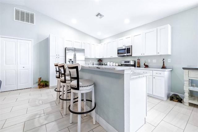 kitchen with appliances with stainless steel finishes, visible vents, a center island with sink, and white cabinetry