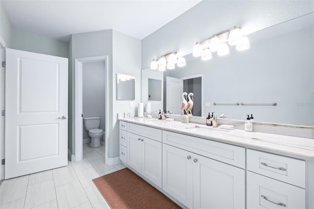 full bath featuring double vanity, a sink, and toilet