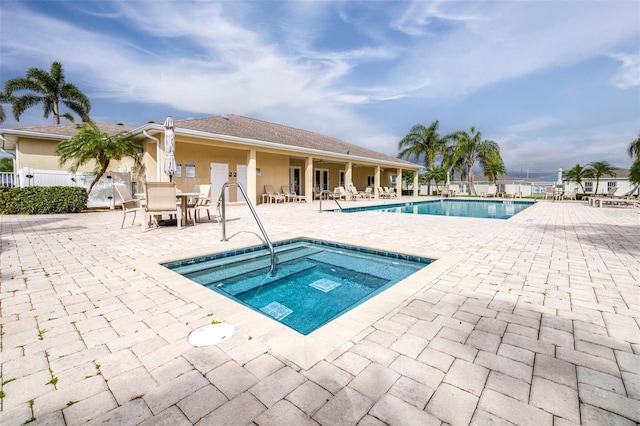 community pool with a patio area, fence, and a community hot tub