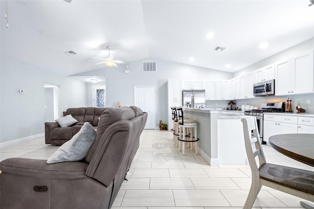 kitchen with visible vents, open floor plan, stainless steel appliances, a kitchen bar, and white cabinetry