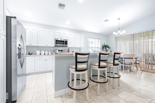 kitchen with stainless steel appliances, visible vents, white cabinets, light countertops, and a center island