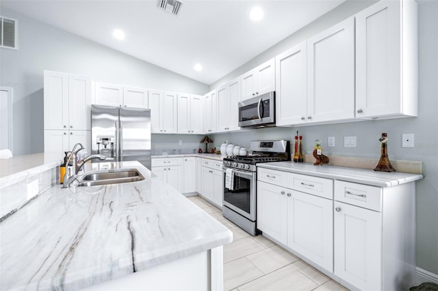 kitchen with visible vents, light stone counters, stainless steel appliances, white cabinetry, and a sink