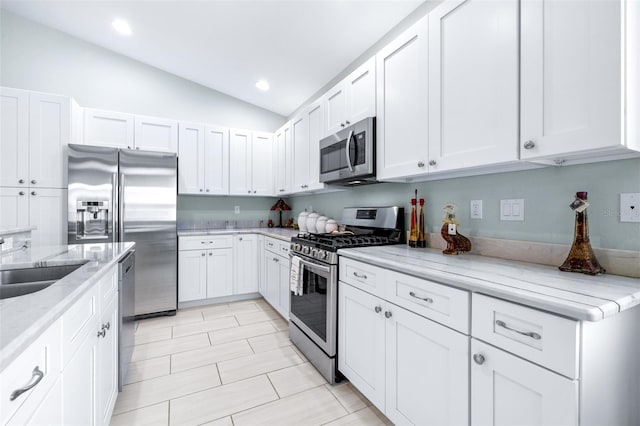 kitchen featuring stainless steel appliances, light stone countertops, and white cabinets