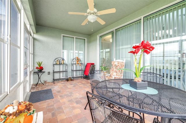 sunroom featuring outdoor dining area, ceiling fan, and a healthy amount of sunlight