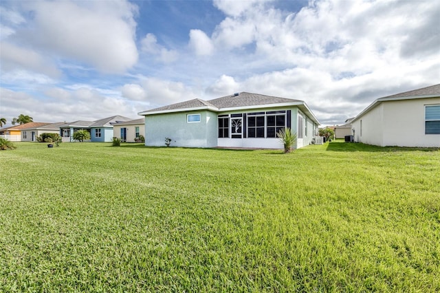 back of house featuring a lawn, a sunroom, and stucco siding