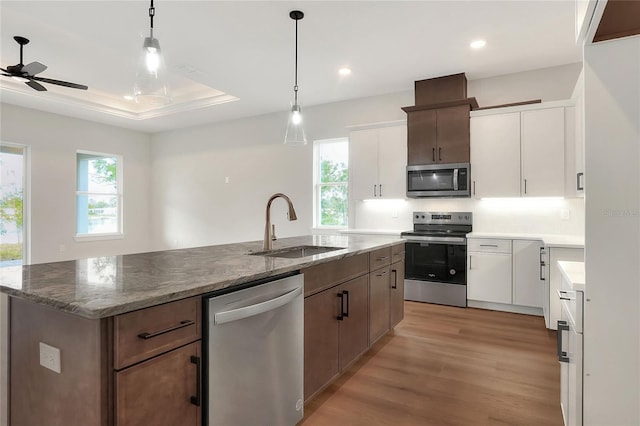 kitchen featuring appliances with stainless steel finishes, an island with sink, white cabinetry, and sink