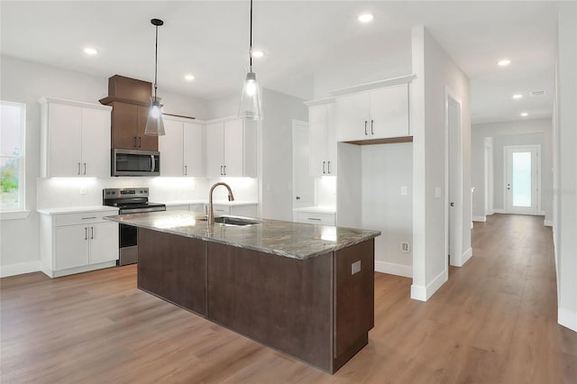 kitchen with white cabinets, sink, dark stone countertops, light wood-type flooring, and appliances with stainless steel finishes