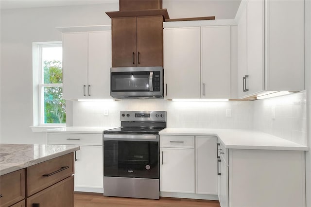 kitchen featuring backsplash, light stone counters, white cabinetry, and stainless steel appliances