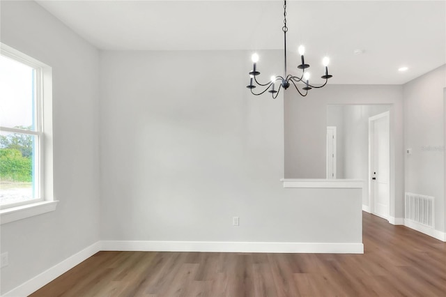 unfurnished dining area with a chandelier and hardwood / wood-style flooring