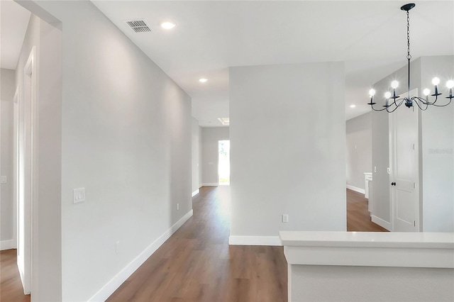 hall with dark wood-type flooring and a chandelier