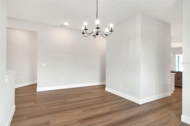 unfurnished dining area with dark hardwood / wood-style flooring and an inviting chandelier