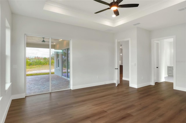 empty room featuring a raised ceiling, ceiling fan, and dark hardwood / wood-style floors