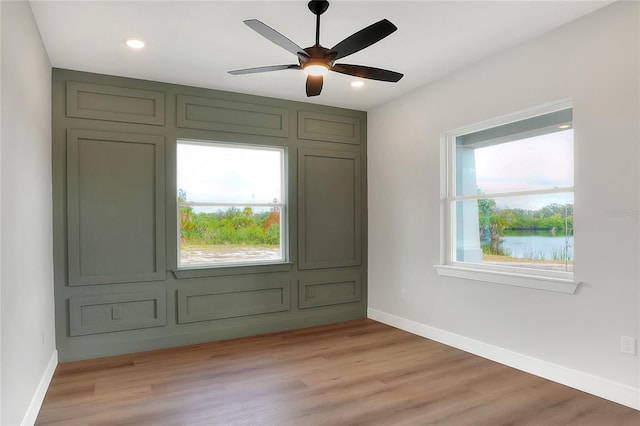 interior space with a wealth of natural light, ceiling fan, a water view, and light wood-type flooring