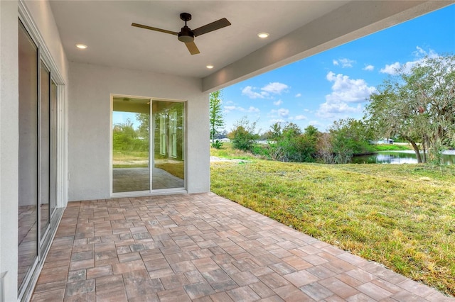 view of patio with a water view and ceiling fan