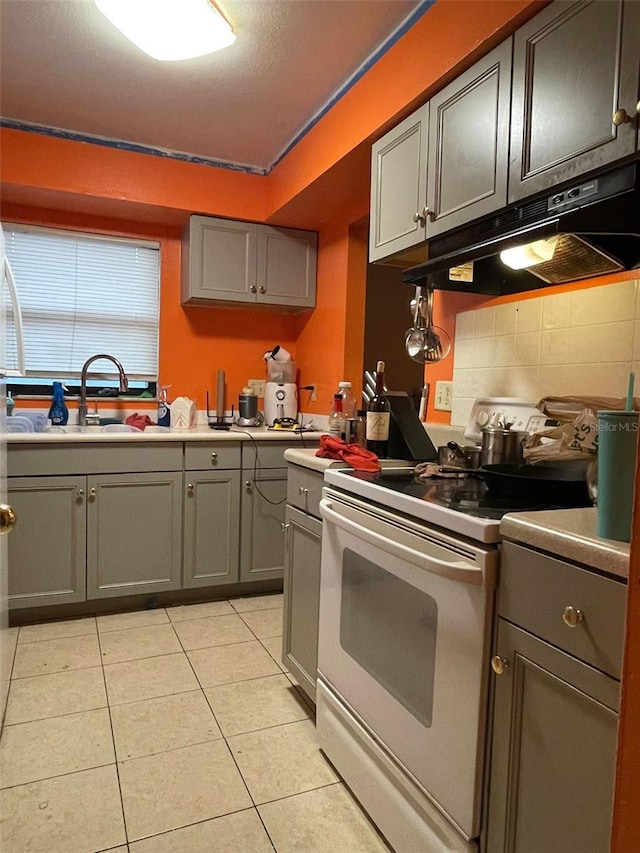 kitchen featuring white range oven, gray cabinetry, sink, and light tile patterned floors