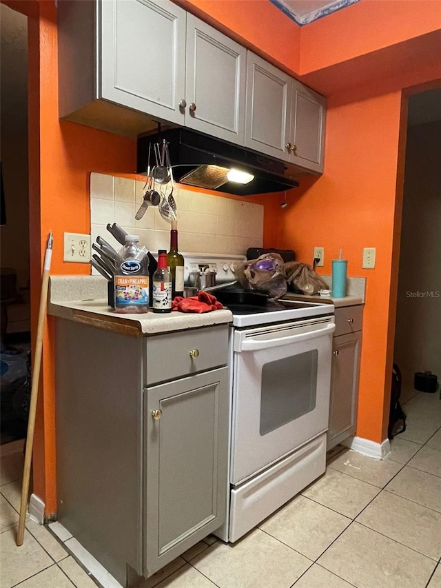 kitchen with white electric range oven, gray cabinets, light tile patterned floors, and tasteful backsplash