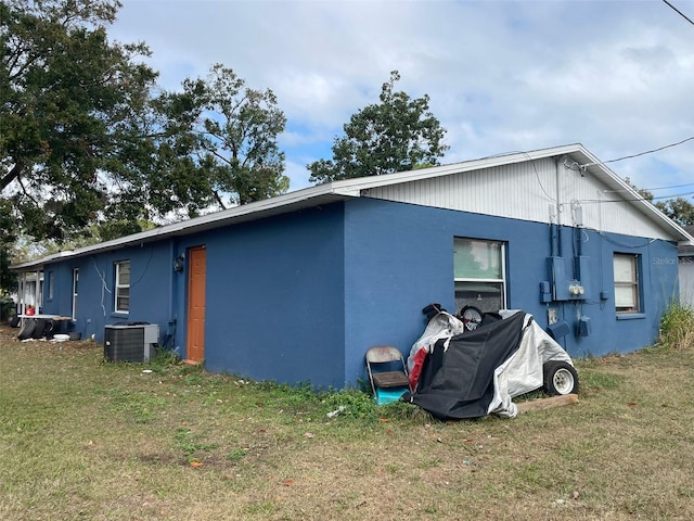 back of house with central AC unit and a yard