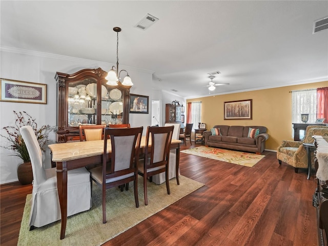 dining area with a wealth of natural light, crown molding, ceiling fan with notable chandelier, and dark hardwood / wood-style floors