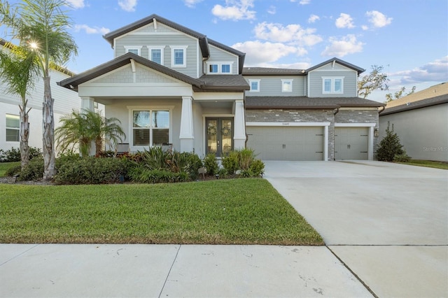 craftsman house with french doors, a garage, and a front lawn