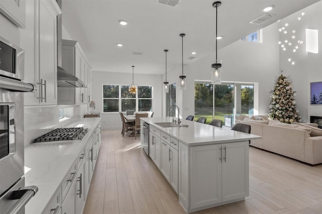 kitchen with sink, white cabinetry, a kitchen island with sink, and hanging light fixtures