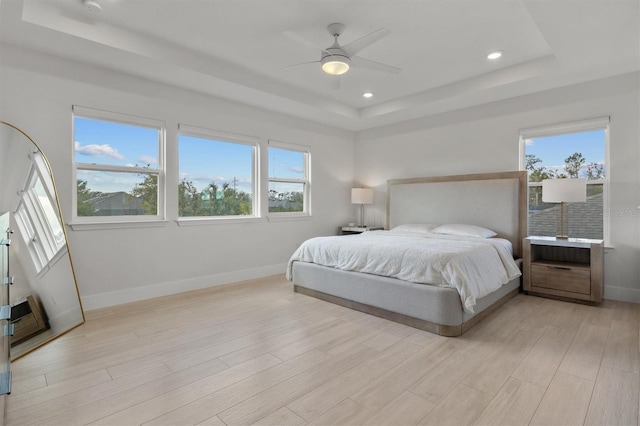 bedroom with a raised ceiling, multiple windows, and ceiling fan